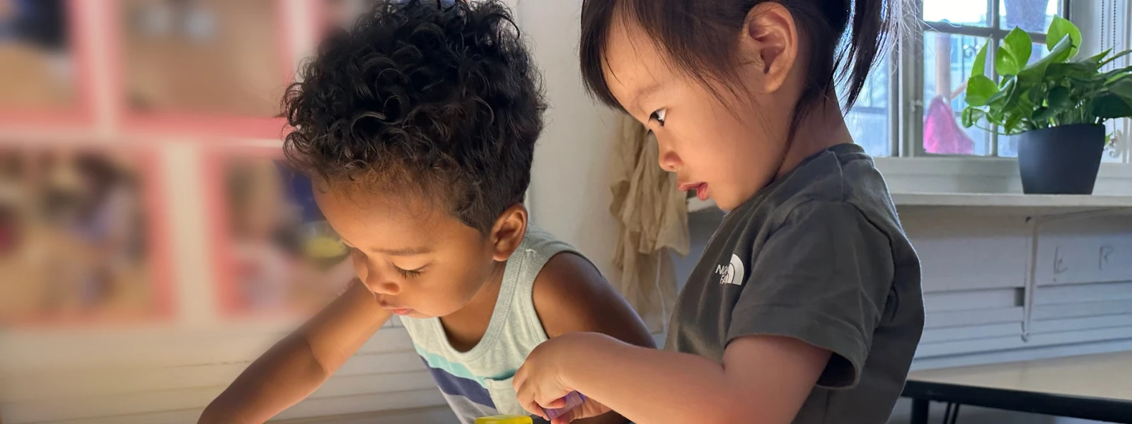 Two children constructing with transparent blocks on a light table, engaging in hands-on exploration and play.