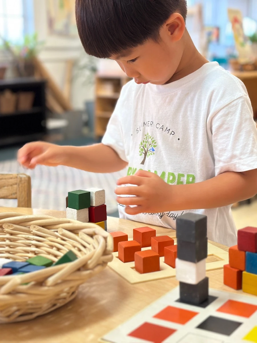 A child using colorful cubes to explore math concepts, including counting, patterning, shapes, balance, symmetry, and so much more, engaging in hands-on learning.